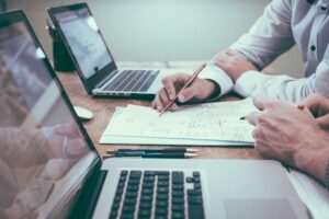 Two people reviewing documents and laptops while discussing a roof insurance claim process