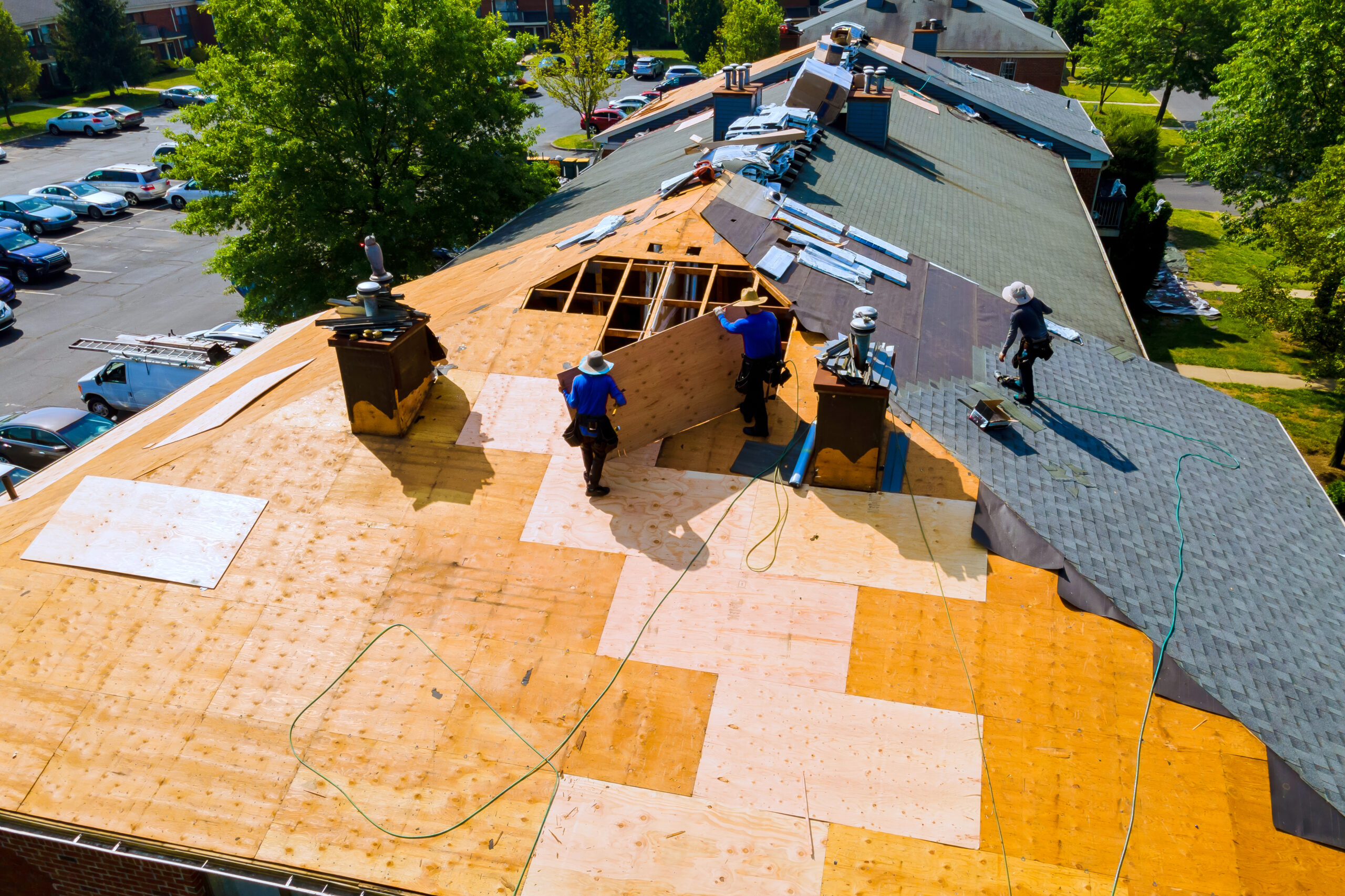 Roofers replacing decking and shingles on a residential home—an example of understanding roofing layers and materials in action.